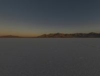 a lone motorcycle is on a barren plain under a cloudy sky in the middle of nowhere