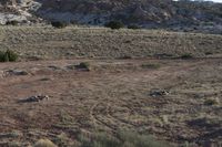 a car in a dry area, near a rocky hill, near some dirt and shrubs