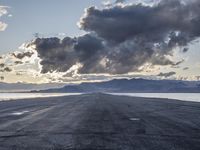 an empty runway on the beach with snow on the horizon and mountains in the background