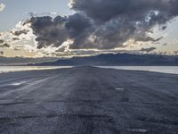 an empty runway on the beach with snow on the horizon and mountains in the background