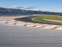 the green road and orange and white stripe line at an event near the racetrack and stadium