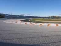 the green road and orange and white stripe line at an event near the racetrack and stadium