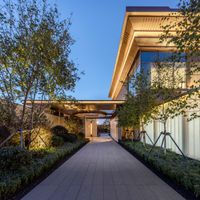 a paved walkway leads from the building to the house through a large windowed door