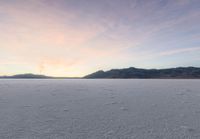 a snow boarder on the ground of a vast snowy landscape with mountains and mountains