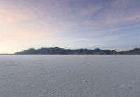 a snow boarder on the ground of a vast snowy landscape with mountains and mountains