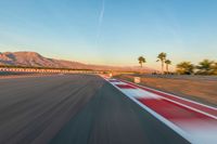 a photo of a dirt race track with sun setting in the distance of the track