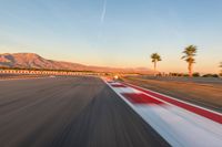 a photo of a dirt race track with sun setting in the distance of the track