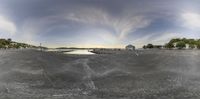 a fish eye view of a lake next to houses, with a bridge in the background