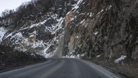 a road that is not paved and full of snow has steep rocks on either side