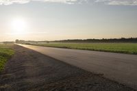 the back of a motorcycle is traveling on a deserted road at sunset - like conditions