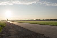 the back of a motorcycle is traveling on a deserted road at sunset - like conditions