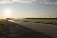 the back of a motorcycle is traveling on a deserted road at sunset - like conditions