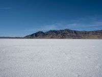 the view over a vast salt plain in the desert with mountains and a blue sky