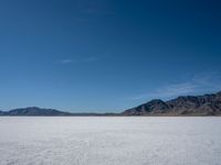 the view over a vast salt plain in the desert with mountains and a blue sky