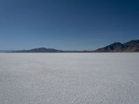 the view over a vast salt plain in the desert with mountains and a blue sky