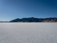 the view over a vast salt plain in the desert with mountains and a blue sky