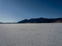 the view over a vast salt plain in the desert with mountains and a blue sky