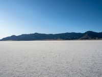 the view over a vast salt plain in the desert with mountains and a blue sky