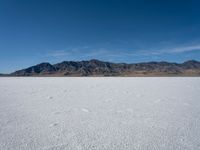 the view over a vast salt plain in the desert with mountains and a blue sky