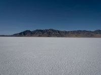 the view over a vast salt plain in the desert with mountains and a blue sky