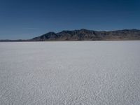 the view over a vast salt plain in the desert with mountains and a blue sky