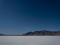 the view over a vast salt plain in the desert with mountains and a blue sky