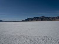 the view over a vast salt plain in the desert with mountains and a blue sky