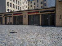 the sidewalk is paved with stones and has a bench in front of it, with no people inside