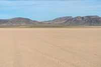 a boy in a hat is riding a motorcycle on a desert plain with mountains in the background