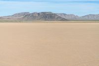 a boy in a hat is riding a motorcycle on a desert plain with mountains in the background