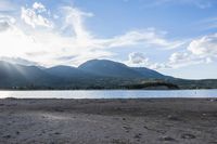 mountains in the distance near some water and rocks at low tide time in a body of water