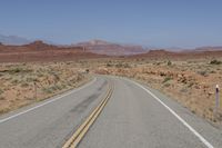 the desert has two roads that are open to traffic with desert in the background and mountain ranges