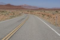 the desert has two roads that are open to traffic with desert in the background and mountain ranges