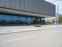 a big building with a few parking spaces in front of it, and two people standing by the curb