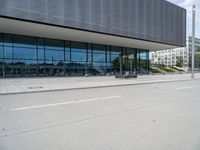 a big building with a few parking spaces in front of it, and two people standing by the curb