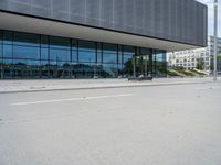 a big building with a few parking spaces in front of it, and two people standing by the curb