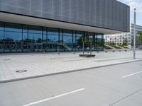 a big building with a few parking spaces in front of it, and two people standing by the curb