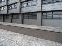 there is a man that is on his bike outside a building that has some windows on the side of it