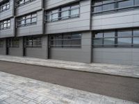 there is a man that is on his bike outside a building that has some windows on the side of it