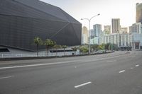 the city street has a building on it in the background, palm trees and other tall buildings