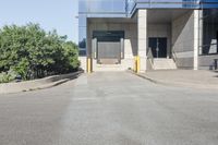 an empty parking lot next to a sidewalk with a building in the background and trees