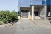 an empty parking lot next to a sidewalk with a building in the background and trees