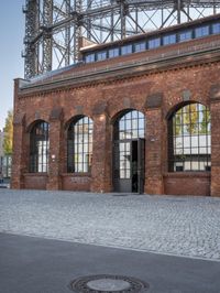 a building made with bricks and a tower on the top with many glass windows, in the background