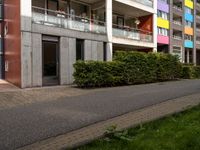 a person riding a bicycle on a sidewalk next to a colorful building with balconies and plants