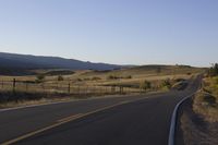 a white fence that surrounds the roadway and mountain range with a road to the front