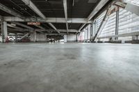 some cars are parked in the large warehouse area of a building, with no people walking on