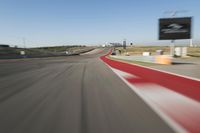 blurry photo of an automobile track with the sign above the camera lens at the moment