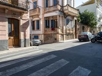 a cross walk on a busy residential street in europe, with buildings behind it and cars parked outside of the building