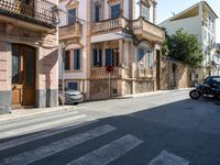 a cross walk on a busy residential street in europe, with buildings behind it and cars parked outside of the building