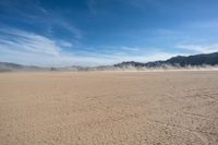 a very sparse desert plain on the side of a mountain, with a dust trail in front of the field